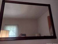 Full view of the large rectangular mirror showing the reflective glass surface and dark wood frame.