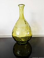 Front view of a vintage green glass vase bottle with a teardrop shape and narrow neck.