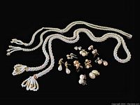 2 faux pearl necklaces with tassel ends and 10 pairs of faux pearl earrings in gold and silver tones on black background