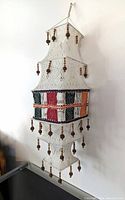 Full view of the 34-inch vintage tiered hanging boho home decor item with woven, crochet fabric and natural wood bead fringe, suspended from a wooden rod.