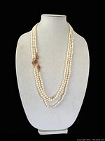 Front view of two of the knotted glass pearl necklaces on a bust form, showing length and pink Swarovski crystal accents