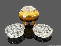 Photo showing the amber glass footed flower frog base with three clear glass inserts arranged around it, highlighting transparent hole patterns and amber color tone.