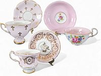 Overview photo showing three bone china tea cups with matching saucers, each with pink and gold patterns. Patterns include fleur-de-lis and floral motifs.
