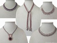 Five handmade beadwork necklaces displayed on busts showing design details and color variation in lilac and purple shades.