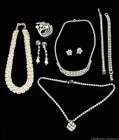 Overview of all 8 pieces arranged against black background. Includes two necklaces with different clasp types, two bracelets, two pairs of earrings, a brooch, and a beaded collar necklace.