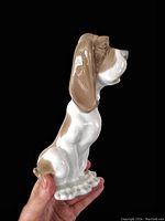 Side view showing the dog’s elongated snout, long ears, and white-and-brown glazed porcelain with unglazed base.