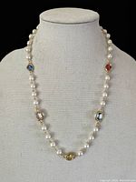 Front view of the necklace on a display bust showing glass pearl beads and colored Swarovski crystals.