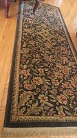 Full view of nylon area rug displaying floral pattern and fringe on wooden floor