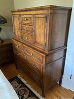 Overall angled front view of two-part dresser showing upper cabinet, lower base and tapered legs
