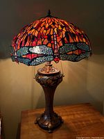 Lamp illuminated showing warm red and amber tones in stained glass shade.