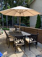 Full patio setup showing table, eight chairs, umbrella open