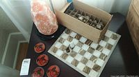 Photo showing the 10-inch salt lamp, stone chess board, and four indigenous design coasters on a table.