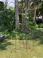 Set of 16 metal shepherds hooks and one additional bird-shaped shepherds hook shown standing upright outdoors, surrounded by garden greenery.
