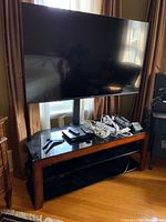 Front view of TV on stand with electronics and cords on lower shelf