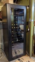 Front view of the wine fridge showing glass door and internal shelving with bottle placeholders.
