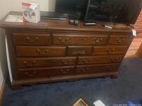 Front view of vintage Broyhill triple dresser showing carved front detail and brass handles on drawers.