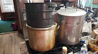 Photo of three large pots stacked: bottom pot is stained large stock pot, middle is metal pot with handles, top is perforated strainer insert pot