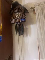 Front view of the traditional wooden cuckoo clock with clock face, figurines, and weights.