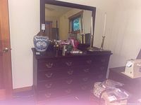 Full view of the dresser with mirror, showing top surface with decorative items and the mirror reflecting room interior.