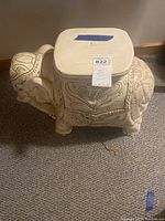 Front side view of ceramic elephant garden stool showing carvings and flat top