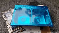 Photo of new stainless steel double bowl kitchen sink covered in blue protective film resting on a box.