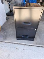 Front view of black 2-drawer file cabinet, showing clean surface and drawer handles.