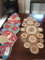Two beaded table runners displayed on a wooden table near a fireplace, showcasing coral and shell themed runner and circular pattern runner.