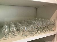Shelf with 32 crystal stemware glasses arranged in rows, showing the full quantity and consistent design.