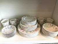 Full view of the dish set showing teacups, saucers, bowls, and stacked plates with floral designs.