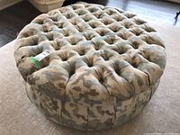 Top and side view of large round tufted upholstered ottoman showing patterned fabric and deep button tufting.