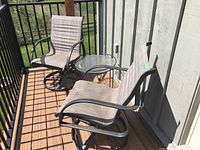 Full set of two swivel chairs and glass top side table shown outside on balcony