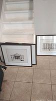 Four framed architectural prints leaning against wall near staircase