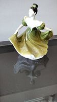Front and side view of Royal Doulton Lady Figurine 'Lynne' in green dress on black surface.
