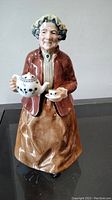 Front view of the Royal Doulton 'Teatime' figurine showing the woman holding a teapot and teacup.