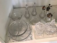 Overview of entire cut glass serving ware lot including cream and sugar set, jam pot, shakers, cruet set, covered box, plates, and trays