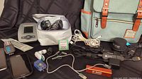 Overview photo showing the blood pressure monitor with cuffs, Fitbit with bands, assorted cell phones, charger cables, Chromecast devices, and Mancio backpack.
