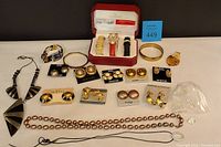 Full lot overview displaying clip-on earrings, bracelets, Peugeot watch with boxes and bands, crystal buttons, and necklaces spread on a flat surface.