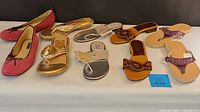 Five pairs of women's shoes arranged in a row, showing different styles including flats and sandals in various colors.