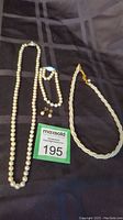 Full view of three pearl jewelry items: the long 21-inch pearl necklace, the shorter 14-inch Napier seed pearl necklace, and the pair of pearl post earrings.