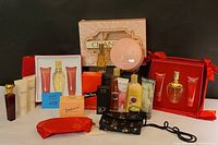 Overview photo showing boxed Escada gift sets, Chantilly powder and Eau de Toilette boxed set, Lauren Ralph Lauren body creams, lotion tubes, a vintage red perfume bottle with gold top, and other assorted items.