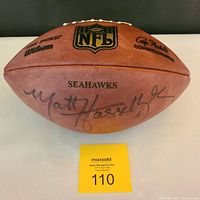 View of NFL football side showing 'SEAHAWKS' text and Matt Hasselbeck signature with auction lot tag.