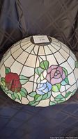 Front view of dome-shaped shade showing off-white glass panels and rose motifs