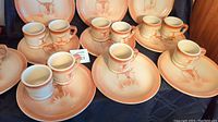 Photo showing multiple plates and coffee mugs arranged with visible Longhorn design and orange gradient coloring.