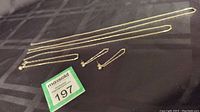 Full view of the long link style silver earrings, bracelet, and two extension chains laid flat on black cloth.