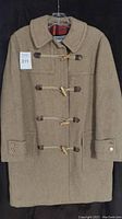 Front view of vintage women's wool duffel coat in camel color with toggle button closures and wide collar.