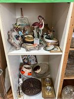 Shelf view with bird-themed decorative items including ceramic flamingos, bird-shaped wall hanging, wooden clock, vases, dishes, and brass candlesticks.