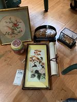 Full lot layout showing the framed stoned and silky paintings, two wood sculptures with carved scenes, Chinese ceramic pot with colorful pattern and scroll rolled and tied.