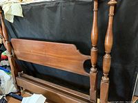Wooden double bed frame headboard with turned posts, showing one missing top pole and worn finish.