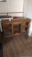 Front view of the wood hutch cabinet with central glass door and side shelves.