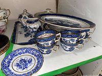 Several pieces of the blue and white Booths fine bone china including stacked teacups, saucers, cream pitcher and various plates.